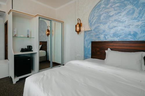 a bedroom with a white bed and a blue painting on the wall at Jannat Regency Jalal-Abad in Jalal-Abad