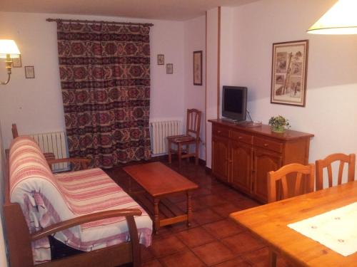 ein Wohnzimmer mit einem TV, einem Tisch und Stühlen in der Unterkunft Apartamentos Petronilla in Benasque