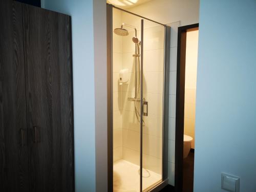 uma casa de banho com um chuveiro e uma porta de vidro em New Work Hotel Essen em Essen