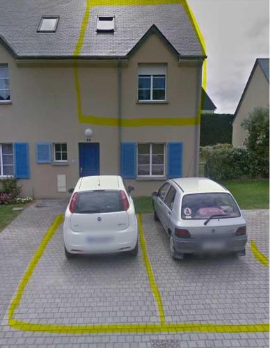 Deux voitures garées sur un parking en face d'une maison dans l'établissement Duplex Barfleur, à Barfleur