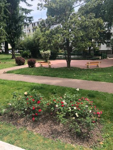 a park with benches and flowers in the grass at Une Chambre dans un appartement in Ablon-sur-Seine