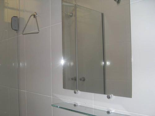 a bathroom with a glass shower with a mirror at Hotel Estação da Fé in Aparecida