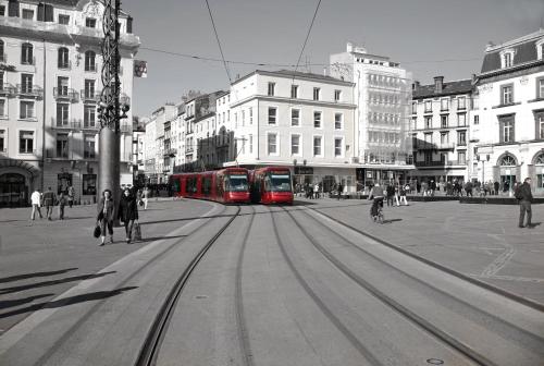 two red trains on a city street with buildings at Kyriad Clermont-Ferrand-Sud - La Pardieu in Clermont-Ferrand