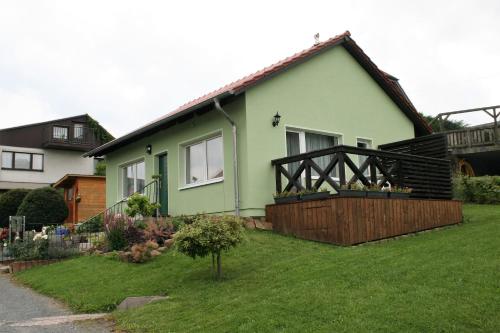 uma casa verde com uma cerca de madeira num quintal em Ferienhaus Grimm em Friedrichsbrunn
