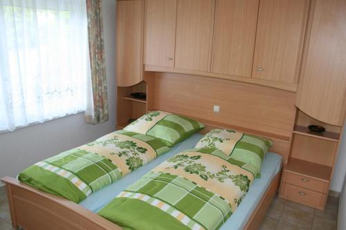 um quarto com uma cama com almofadas verdes e brancas em Ferienhaus Grimm em Friedrichsbrunn