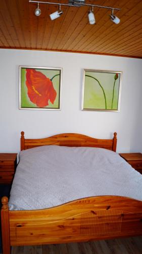 1 dormitorio con cama de madera y 2 cuadros en la pared en Ferienwohnung Familie von Seggern, en Bispingen