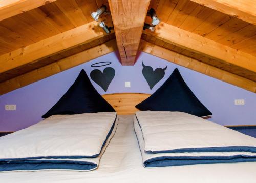 - une chambre avec 2 lits avec des cœurs sur le mur dans l'établissement Ferienhaus Hexenschlummer - Schlafzimmer und romantischer Schlafboden, à Thale