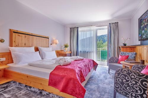 a bedroom with a large bed with a red blanket at Hotel Reinerhof in Sankt Englmar