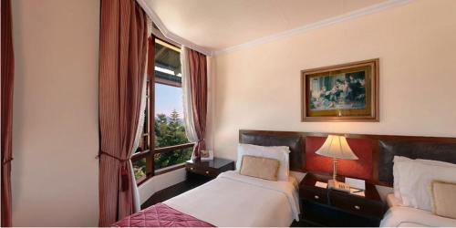 a hotel room with two beds and a window at The Elgin Silver Oaks - Heritage Resort & Spa in Kalimpong