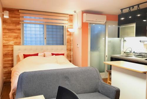 a bedroom with a bed and a chair and a kitchen at Ryu Guest House Gangnam in Seoul