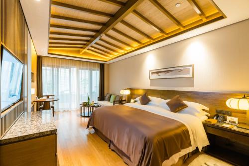 a bedroom with a large bed and a flat screen tv at S&N Zhejiang LinHai International Hotel in Linhai
