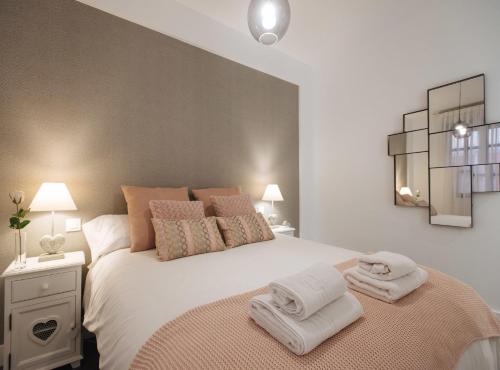 una camera da letto con un grande letto bianco con asciugamani di Luxury Apartment in Plaza de Armas a Siviglia