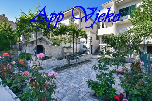 a sign for a villa with flowers in a courtyard at Apartments Vjeko in Makarska