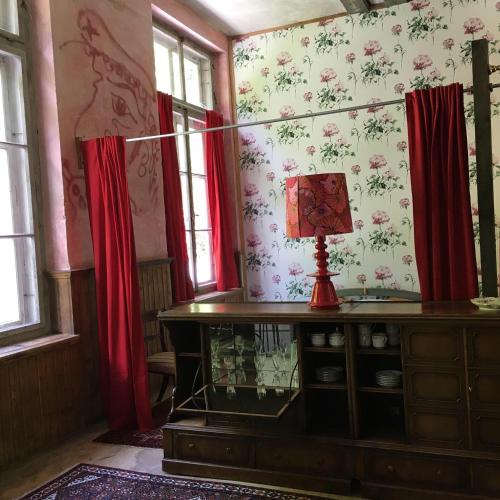 a room with red curtains and a table with a lamp at Loft Chupferhammer & Loft Factory in Ober-Bazenheid