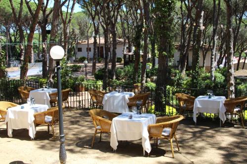 a restaurant with white tables and chairs and trees at Hotel Garbi in Calella de Palafrugell