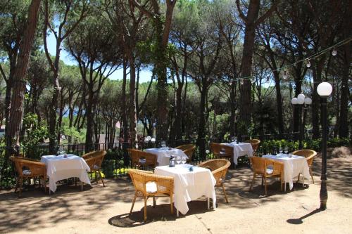 a restaurant with white tables and chairs and trees at Hotel Garbi in Calella de Palafrugell