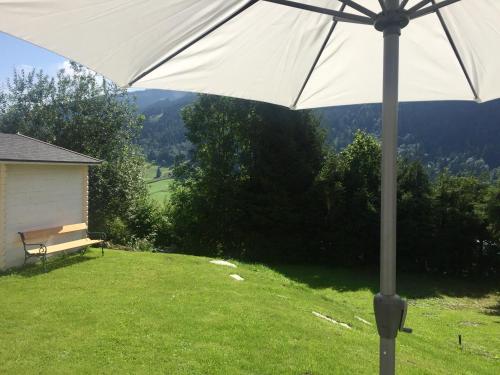 a white umbrella in a yard with a bench at Chalet Kaprun in Kaprun