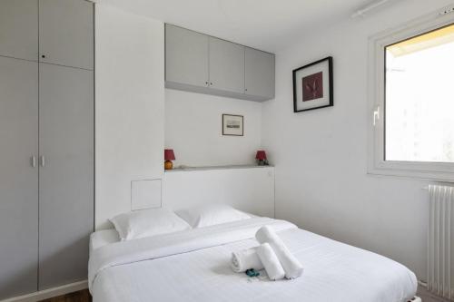 um quarto branco com uma cama com toalhas em Sunny & quiet 2br near the Eiffel Tower Invalides Beaugrenelle Welkeys em Paris