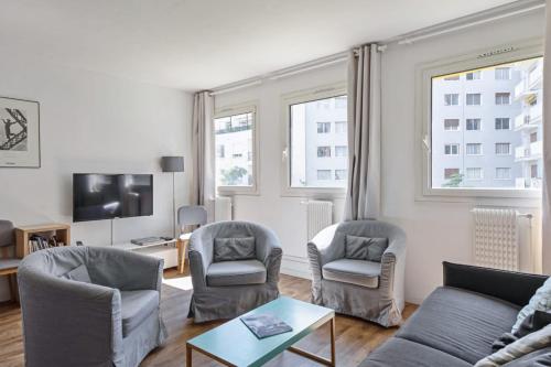 ein Wohnzimmer mit einem Sofa und zwei Sesseln und einem Fernseher in der Unterkunft Appartement de la Motte - Welkeys in Paris