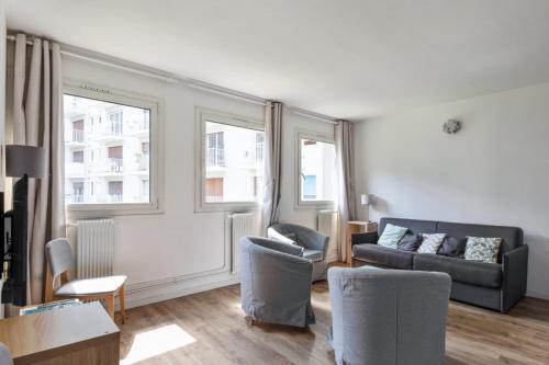uma sala de estar com um sofá e duas janelas em Sunny & quiet 2br near the Eiffel Tower Invalides Beaugrenelle Welkeys em Paris