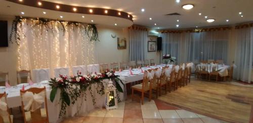a banquet hall with white tables and chairs with roses at Pasja in Kwidzyn