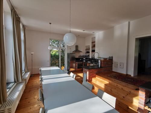 a dining room with white tables and a kitchen at Gutshaus Thorstorf FeWo Boltenhagen EG und Tiefpaterre in Warnow