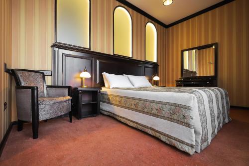 a bedroom with a bed and a chair and a mirror at Attache Hotel in Kyiv