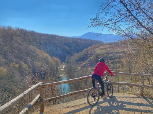 a person riding a bike on a fence overlooking a river at 16 Lakes Hotel in Grabovac