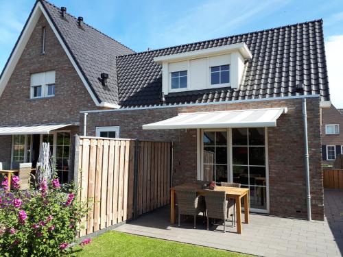 a house with a white awning on a patio at De Sprink - Vakantiewoning in Zoutelande