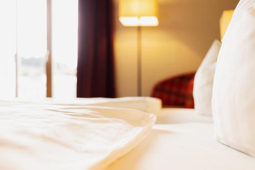 a white bed in a hotel room with a window at Hotel Ahornhof in Lindberg