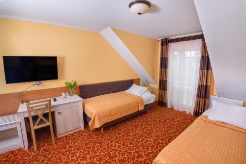 a hotel room with two beds and a desk at Pensjonat Cezar in Siemiatycze