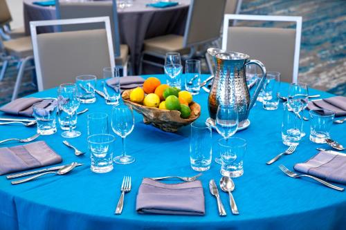 a blue table with a bowl of fruit and a vase at EVEN Hotel Miami - Airport by IHG in Miami