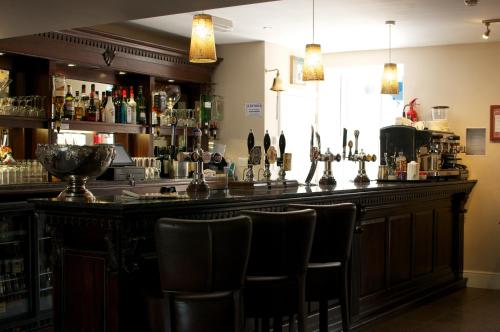 a bar with chairs in a room with alcohol at The Three Horseshoes Hotel in Barnard Castle