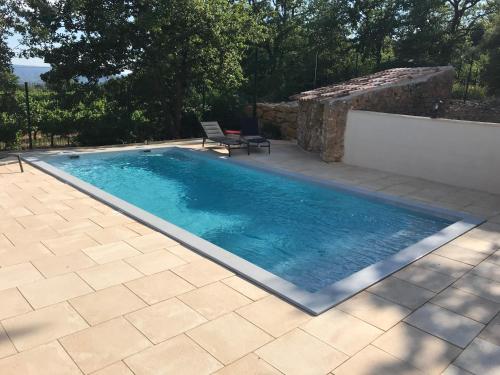 una piscina en un patio con una pared de piedra en La Bastide de l'Olivier, en Flassan