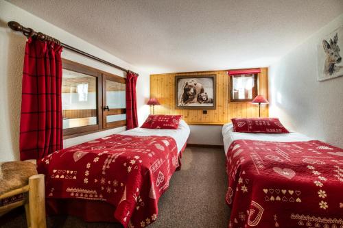 two beds in a hotel room with red sheets at Club Alpina - Champagny-en-Vanoise in Champagny-en-Vanoise