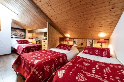 two beds in a room with red and white blankets at Club Alpina - Champagny-en-Vanoise in Champagny-en-Vanoise