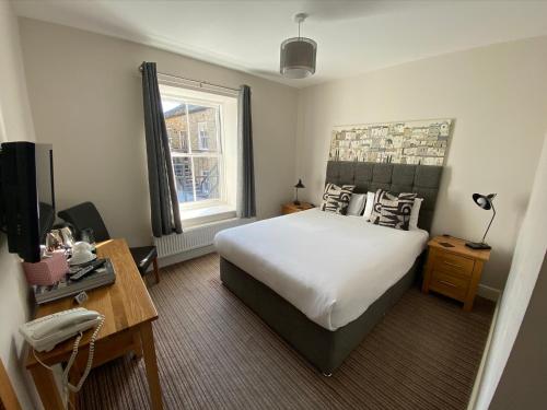 um quarto com uma cama e uma secretária com um telefone em The Three Horseshoes Hotel em Barnard Castle