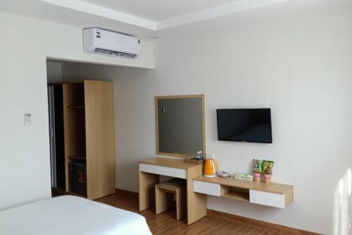 a bedroom with a bed and a desk with a television at Galaxy Hotel in Quy Nhon