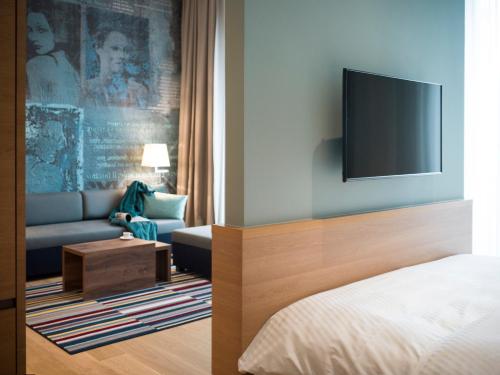 a bedroom with a bed and a couch and a tv at The Wellem, in The Unbound Collection by Hyatt in Düsseldorf