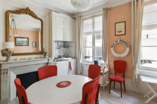 une cuisine avec une table blanche et des chaises rouges dans l'établissement Appartement des Embruns - Welkeys, à Trouville-sur-Mer