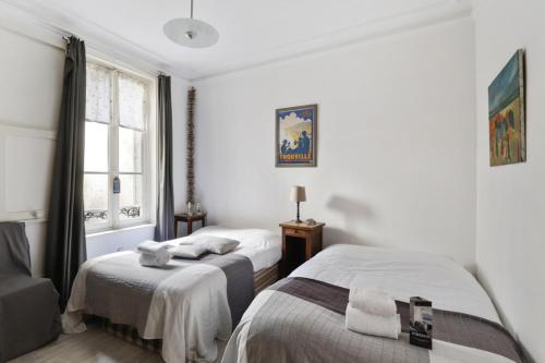 une chambre avec deux lits et une fenêtre dans l'établissement Appartement des Embruns - Welkeys, à Trouville-sur-Mer