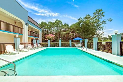 a swimming pool with chairs and a fence at Baymont by Wyndham McDonough in McDonough