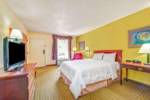 a hotel room with a bed and a flat screen tv at Baymont by Wyndham McDonough in McDonough