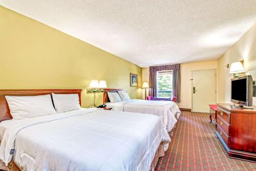 a hotel room with two beds and a flat screen tv at Baymont by Wyndham McDonough in McDonough