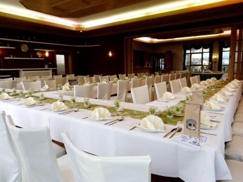 a row of white tables and chairs in a room at Ferienhotel Wolfsmühle in Rodishain