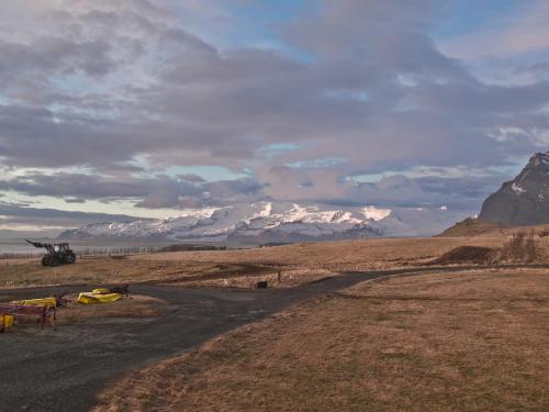 a helicopter parked in a field with mountains in the background at Skyrhusid Guesthouse in Hali