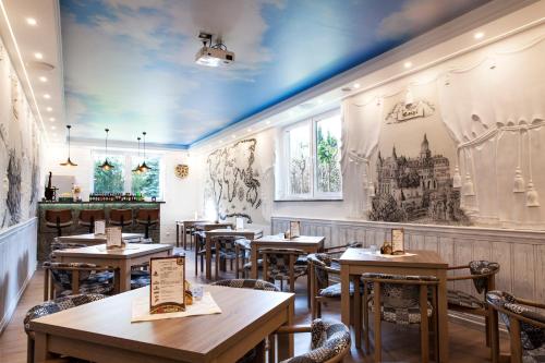 un restaurant avec des tables et des chaises en bois et des peintures sur les murs. dans l'établissement Villa Karpacz, à Karpacz