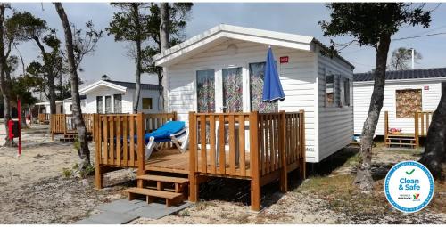 a white tiny house with a large deck at Mira Lodge Park in Praia de Mira