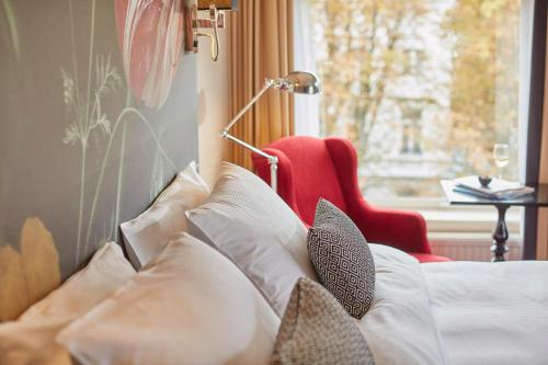 - un canapé avec des oreillers et une chaise rouge à côté d'une fenêtre dans l'établissement Carlton Ambassador, à La Haye