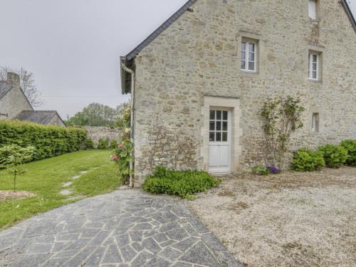 ein Steinhaus mit einer weißen Tür und einem Hof in der Unterkunft Holiday Home Omaha Beach with Garden in Aignerville